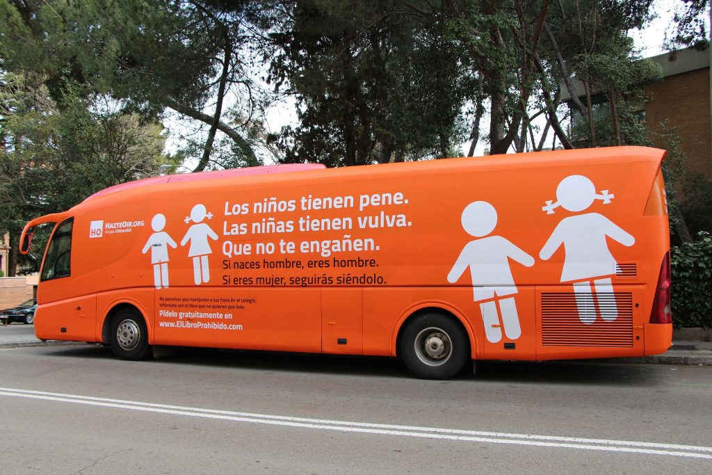 Transphobic bus chartered by HazteOír (Make Yourself Heard) on February 27. The bus reads "Boys have penises. Girls have vulvas. Don't be fooled. If you were born a man, you're a man. If you're a woman, you'll keep being one. Don't let them manipulate your kids at school. Inform yourself with the book they don't want you to read. Order it for free at ElLibroProhibido.com