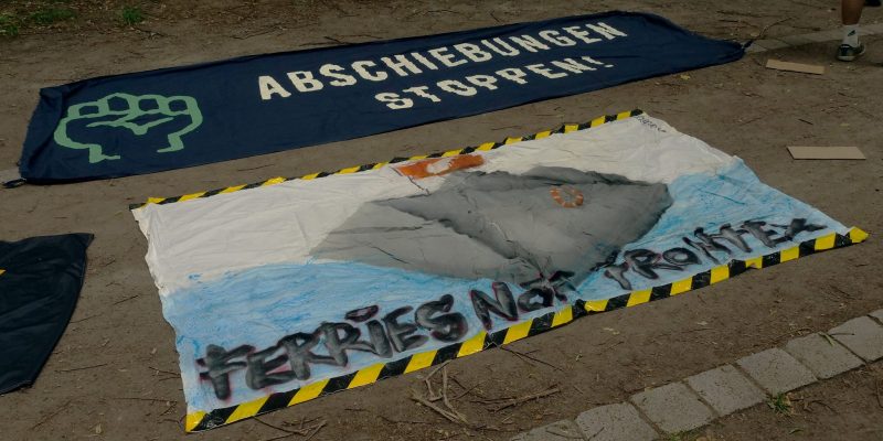 Two protest banners lie on the floor at a pro-migrant protest in Leipzig, reading "Stop Deportations" and "Ferries not Frontex".