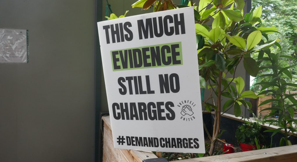 A Grenfell United placard reading "This much evidence still no charges"