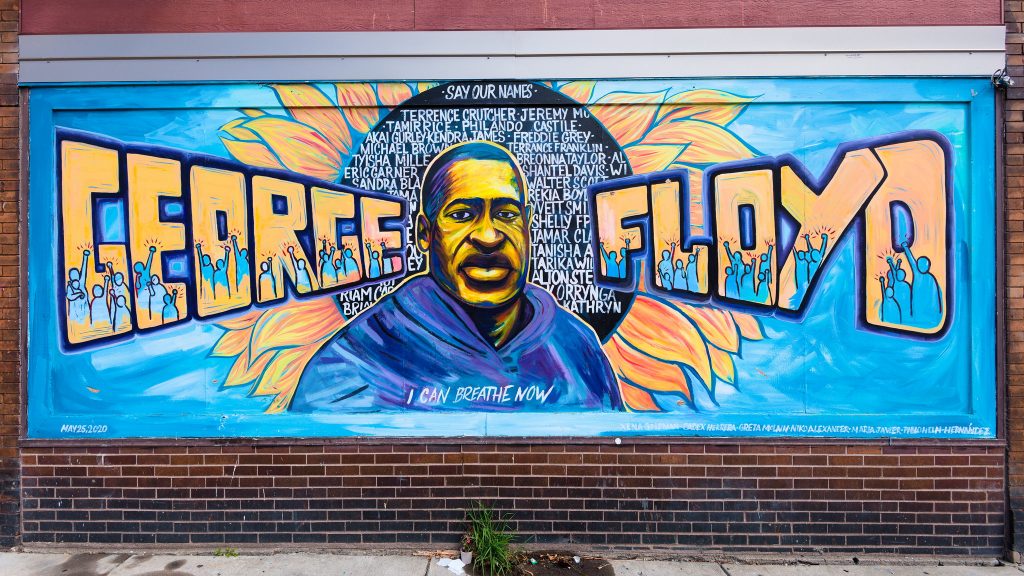 A George Floyd mural in Minneapolis, with an image of Floyd in the centre, his name and surname on either side, and the names in small text of other black people killed by police.