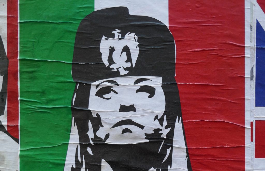 A poster on a wall in London showing the head of far-right Italian PM Giorgia Meloni wearing a hat with the Mussolinian fascist eagle symbol